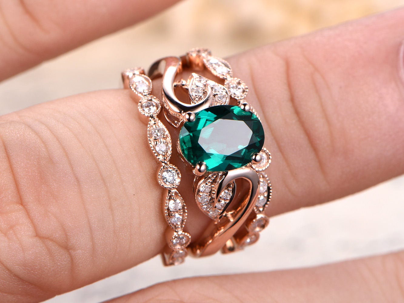 Ensemble de bague de fiançailles en or rose 14 carats comprenant une émeraude ovale et deux alliances perlées.