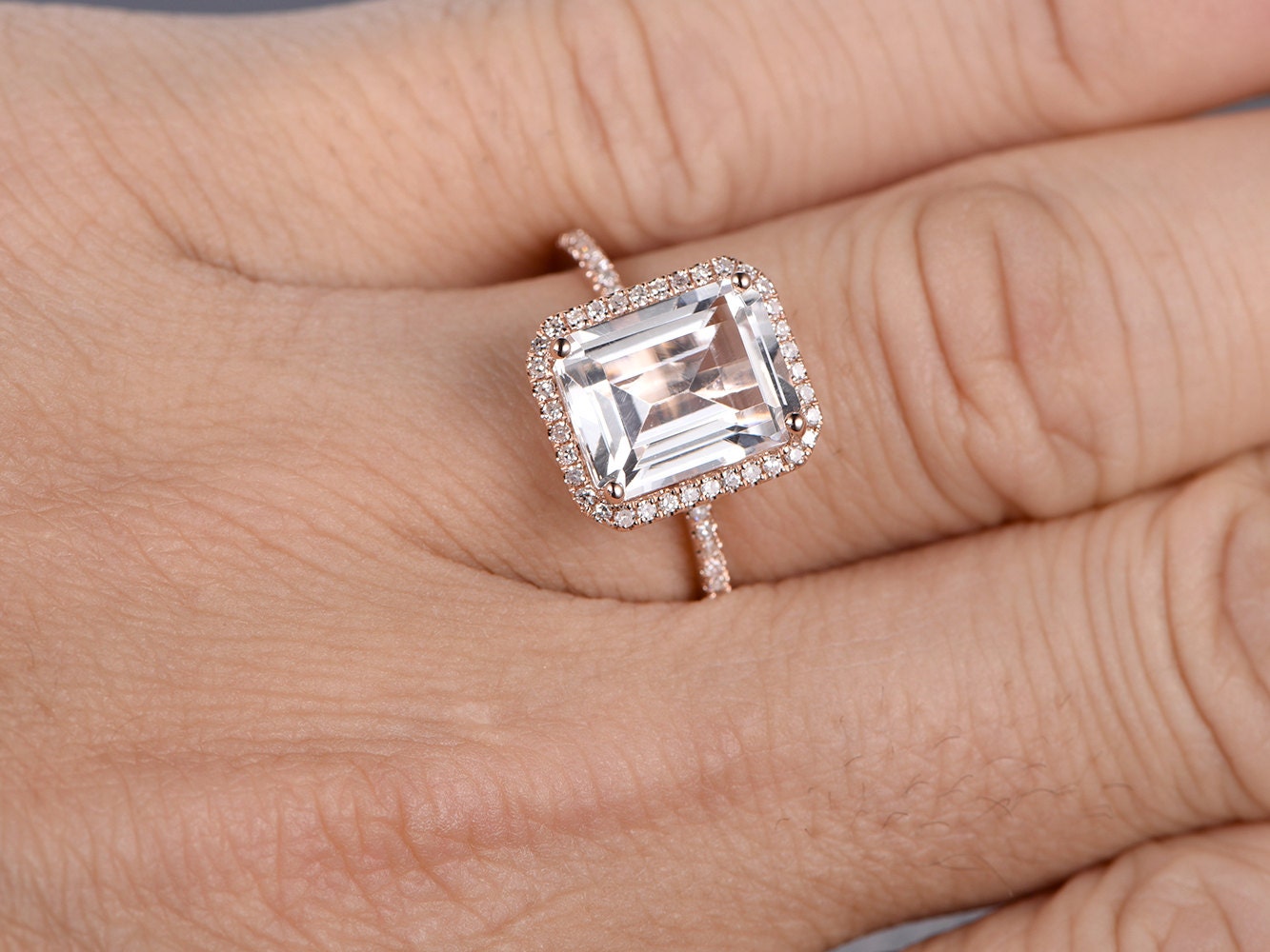 Bague de fiançailles en topaze blanche taille émeraude 8x10 mm, or rose 14 carats, sertie de diamants et ornée d'un halo. Disponible avec topaze bleue et émeraude.